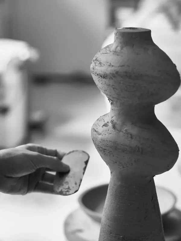 Hands shaping a stacked ceramic form