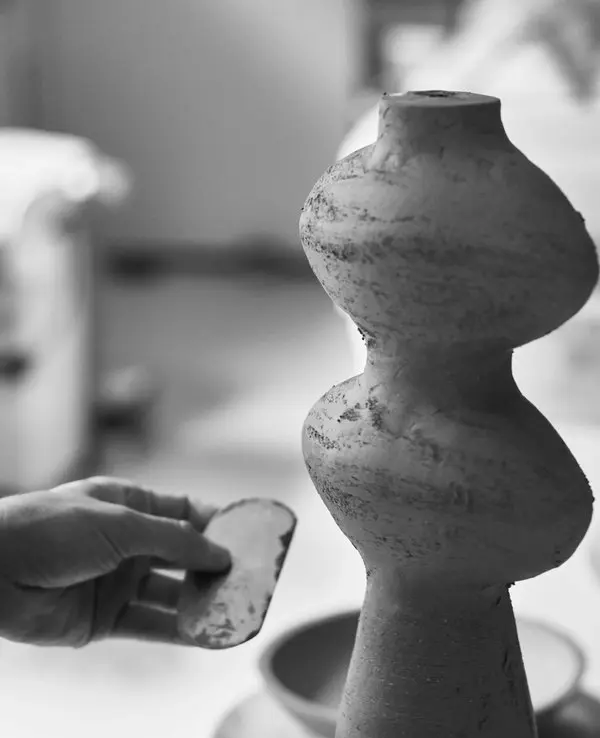 Hands shaping a stacked ceramic form