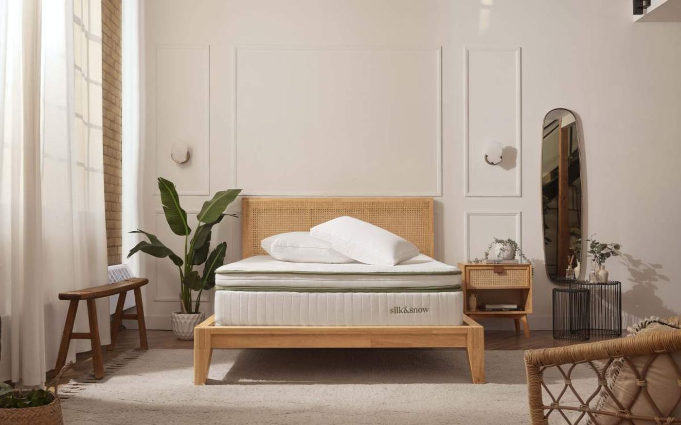 Bright bedroom with Silk & Snow pillows on a mattress and wooden bed frame