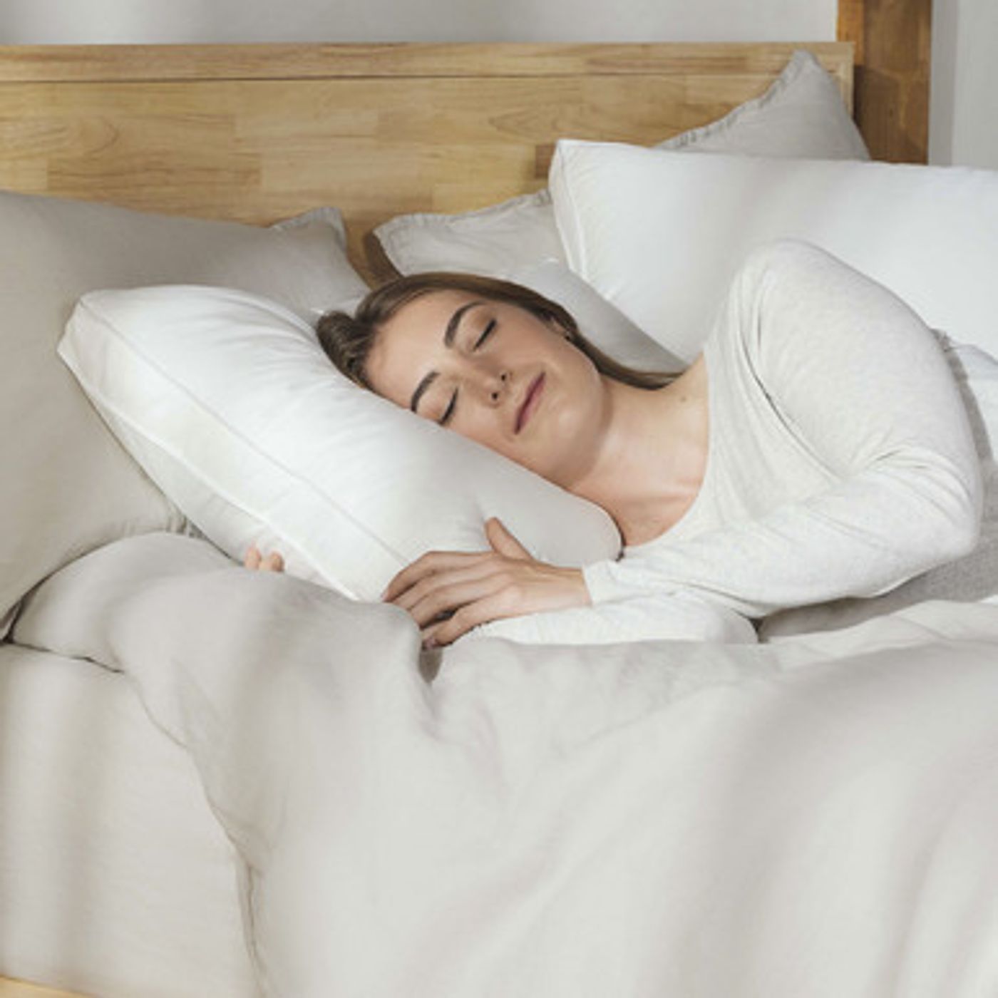 Woman sleeping on her side on a white Silk & Snow Reserve Down Pillow