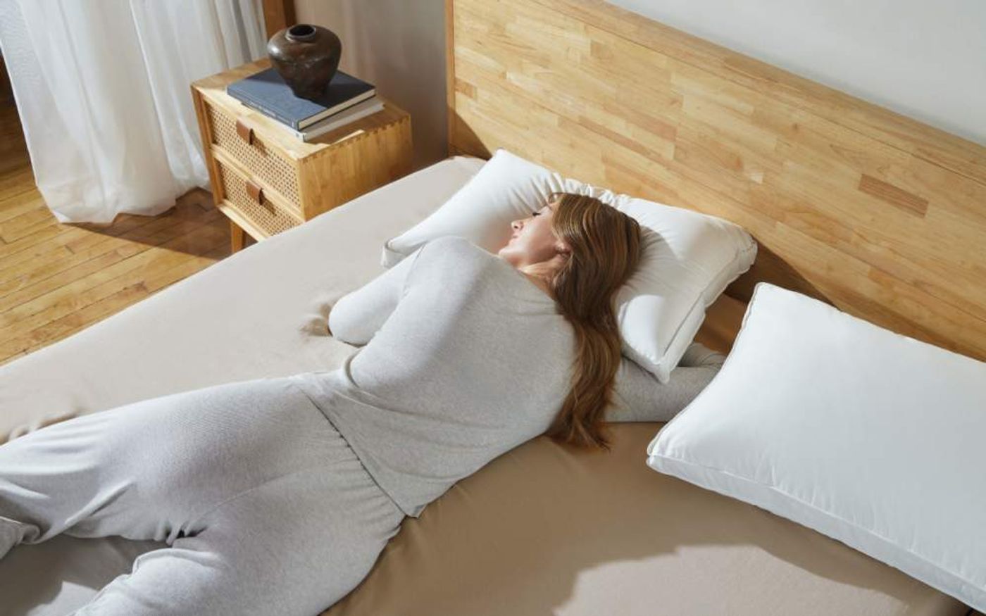 Woman sleeping on her stomach, hugging a Silk & Snow Reserve Down Pillow