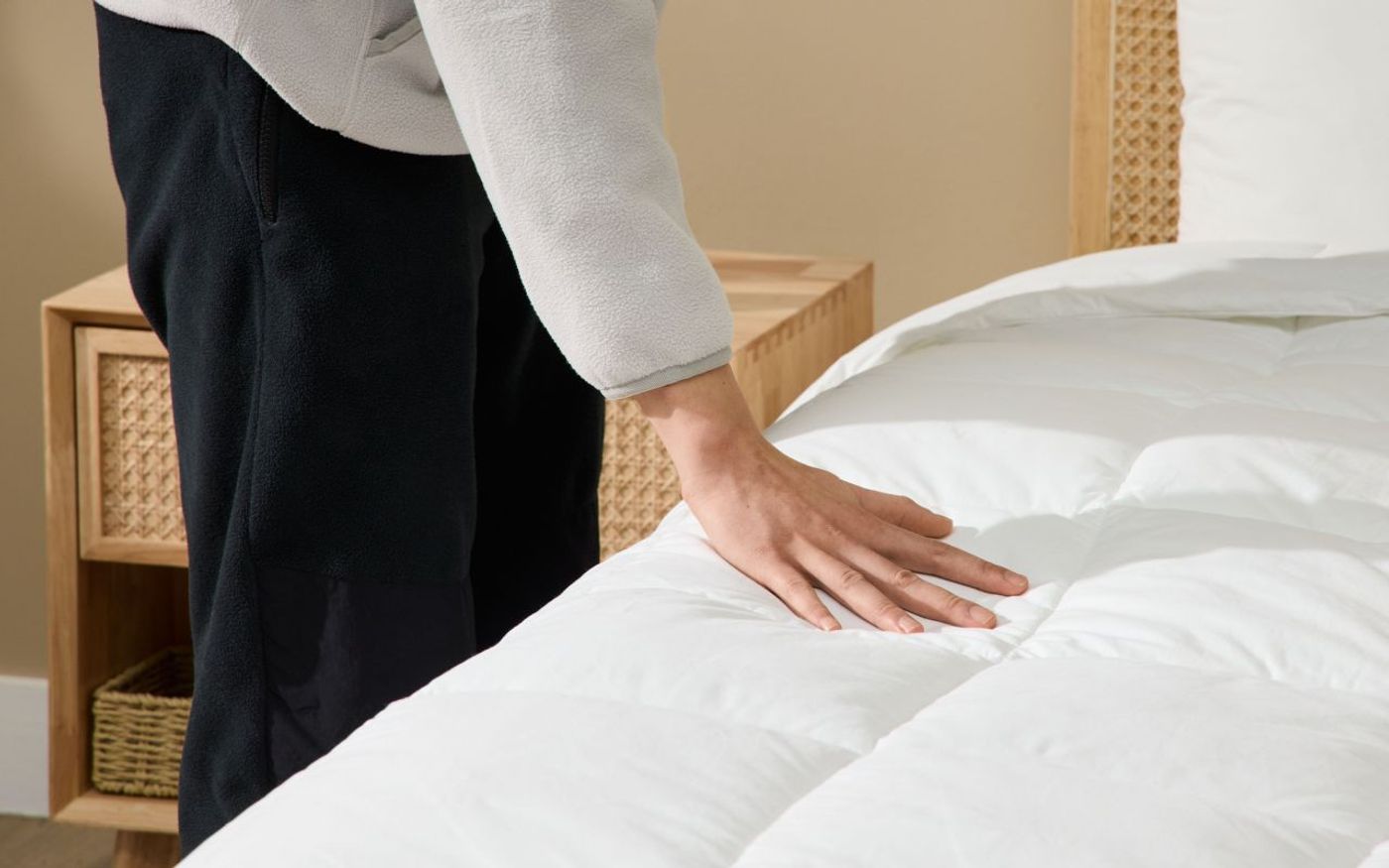 Person smoothing out a white Silk & Snow Down Alternative Duvet on a bed