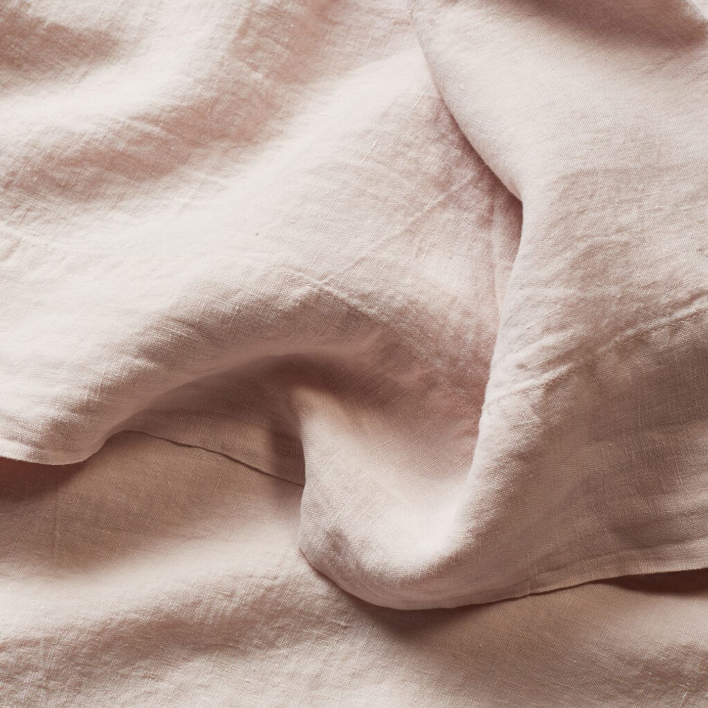 Close-up of the soft, rumpled texture of blush pink flax linen sheets