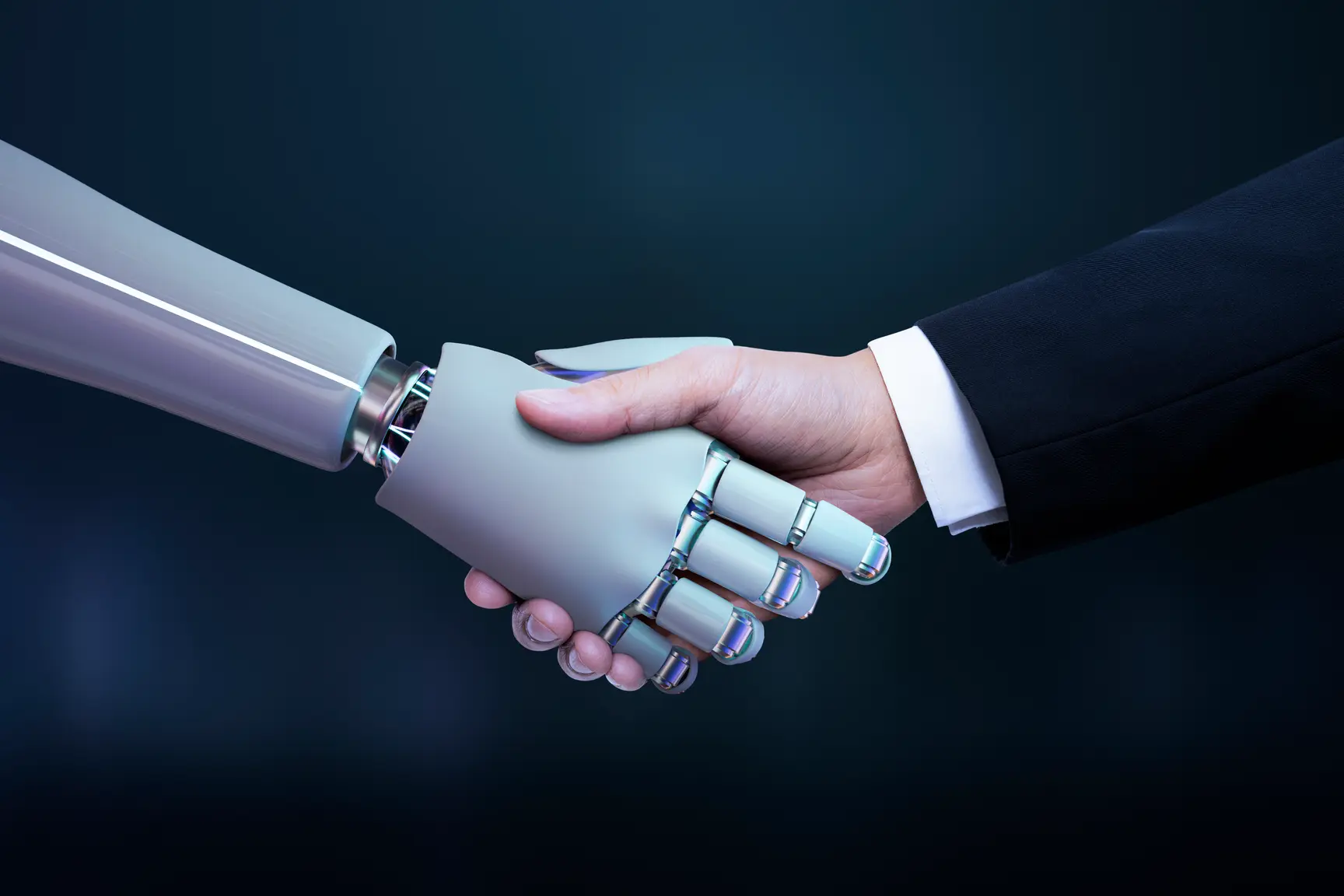 A robotic hand and a human hand in a business suit shake hands against a dark blue background, symbolizing partnership between humans and artificial intelligence or technology.