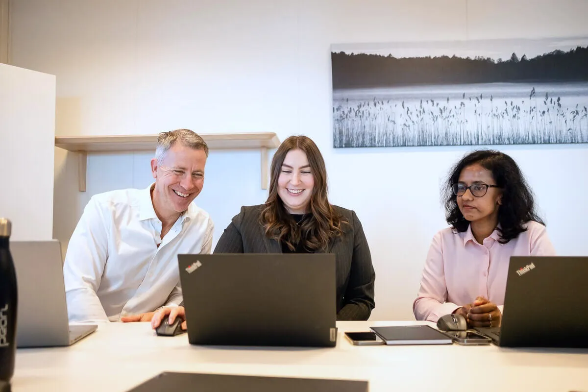 three people sitting by laptop
