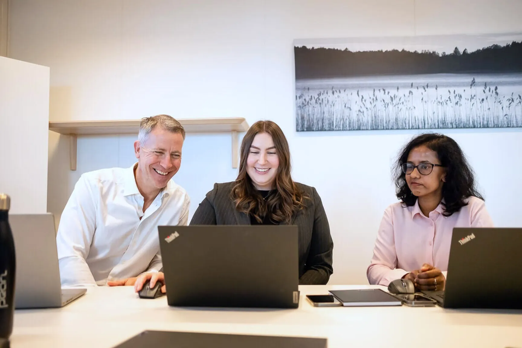 three people sitting by laptop