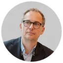 Male in glasses and black jacket and airpod in his ear.