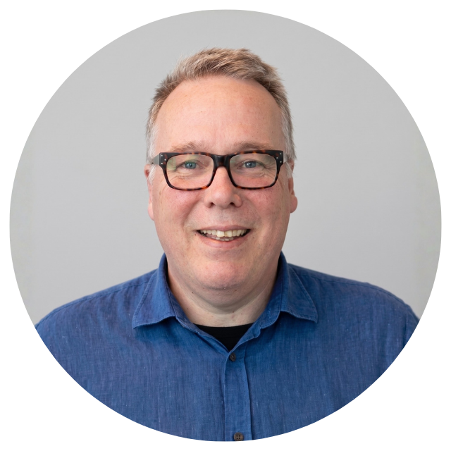 Smiling man in a blue shirt and glasses.