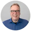Smiling man in a blue shirt and glasses.