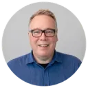 Smiling man in a blue shirt and glasses.