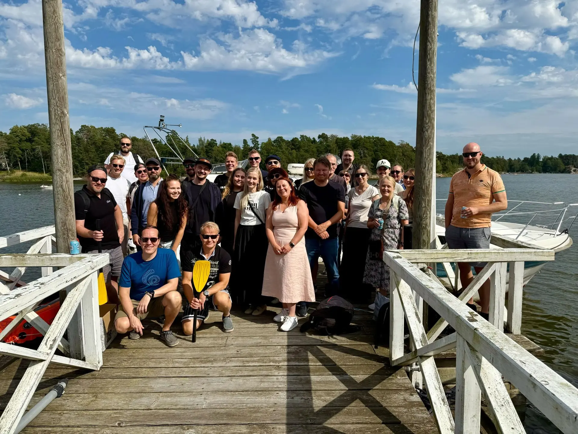 Group of people standing on deck outside in the sunshine