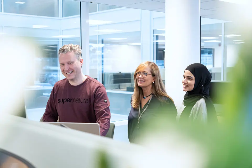 Three people looking at a screen.