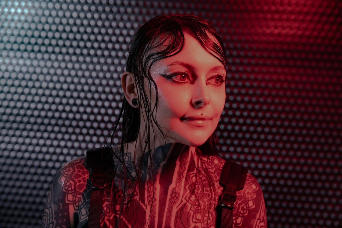 Krista Bourgeois facing right under red light against a metallic studio backdrop