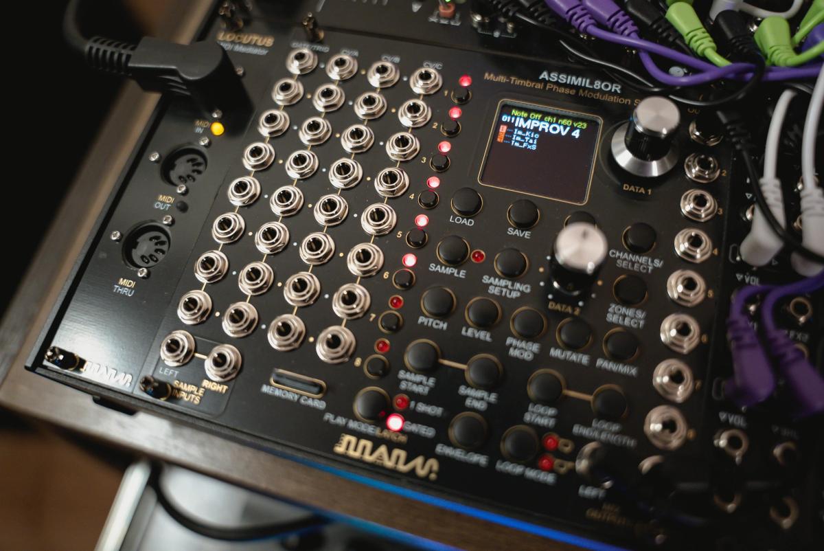 Close-up of an Assimil8or sampler module with its illuminated display and rows of patch sockets