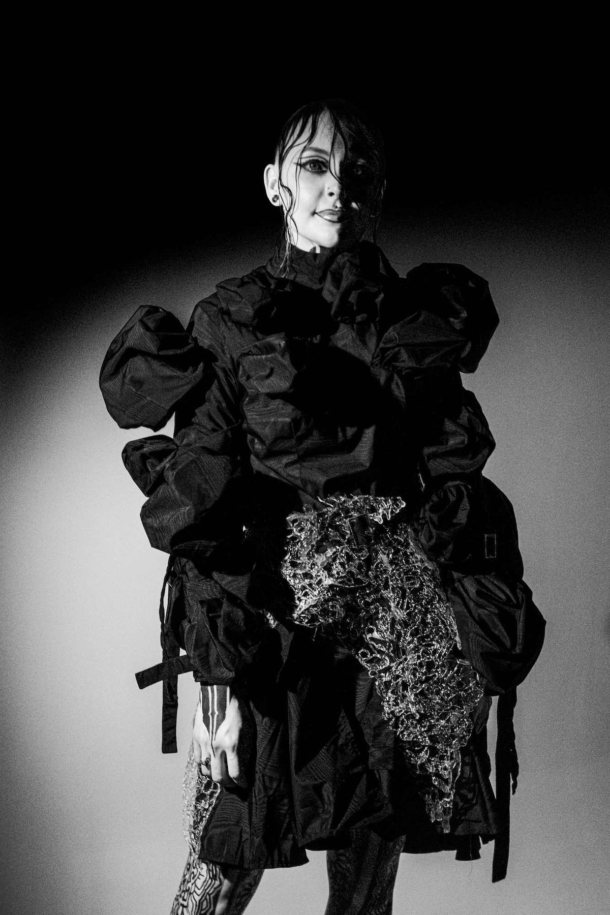 Krista wearing a voluminous ruffled outfit in a black and white studio portrait