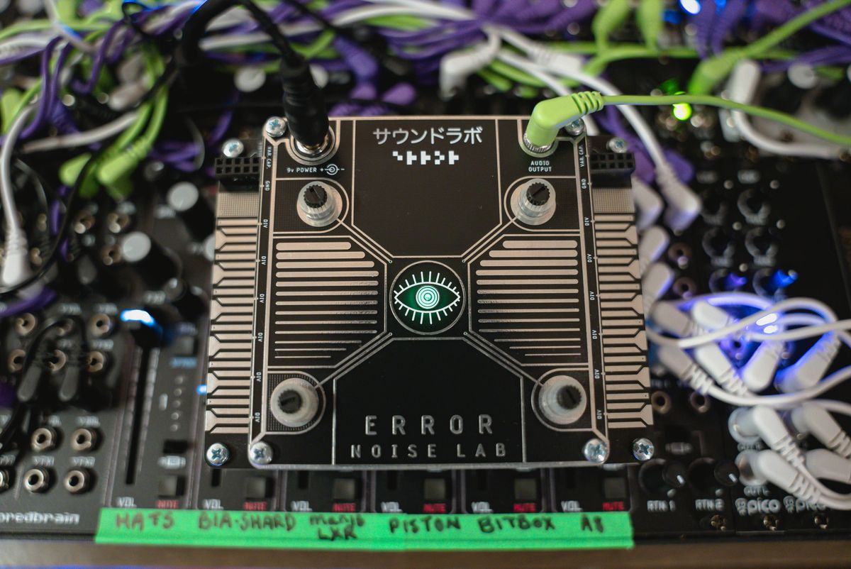 An Error Noise Lab module held above the case, showing its gold circuit-like front-panel design
