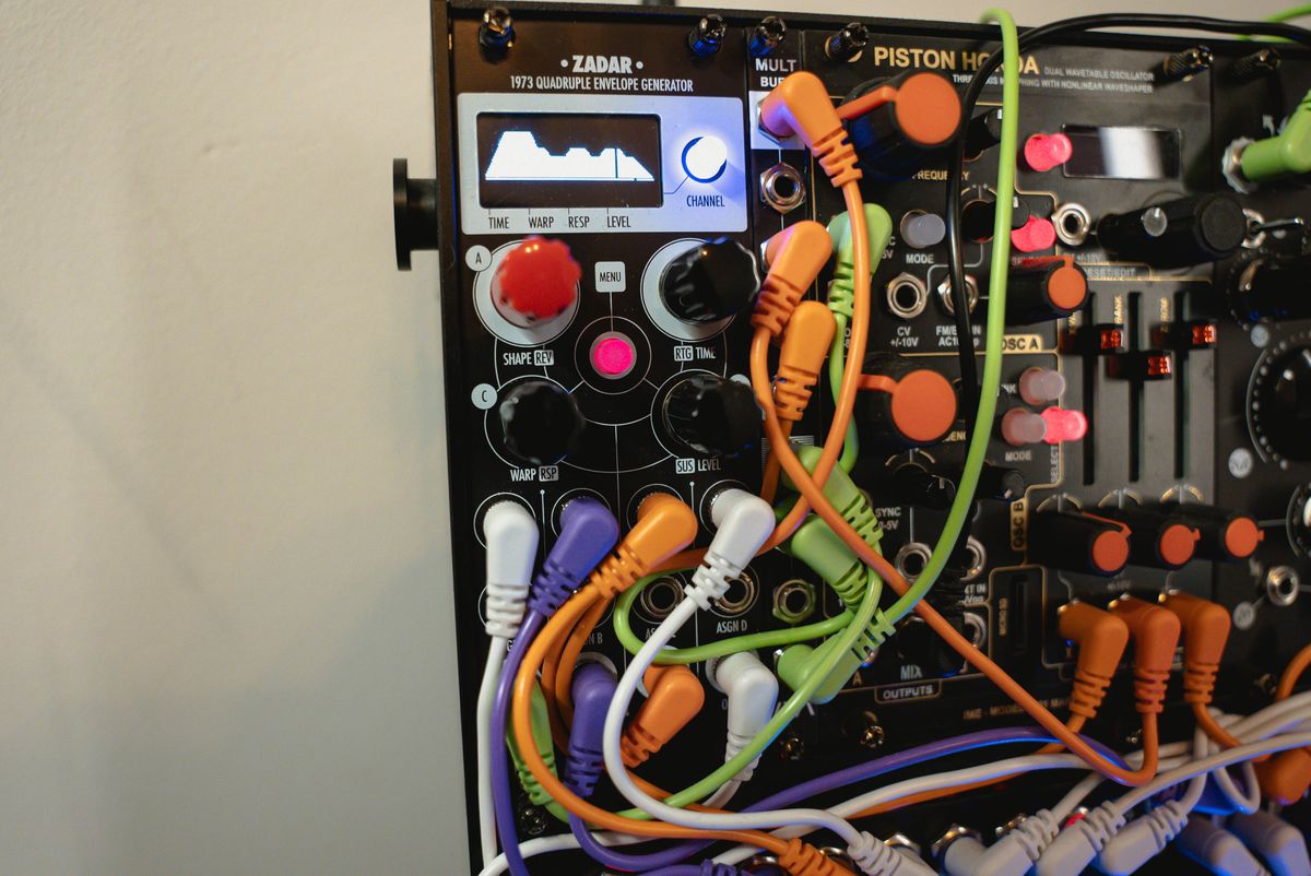 Close-up of a Zadar module with its illuminated waveform display and patched cables
