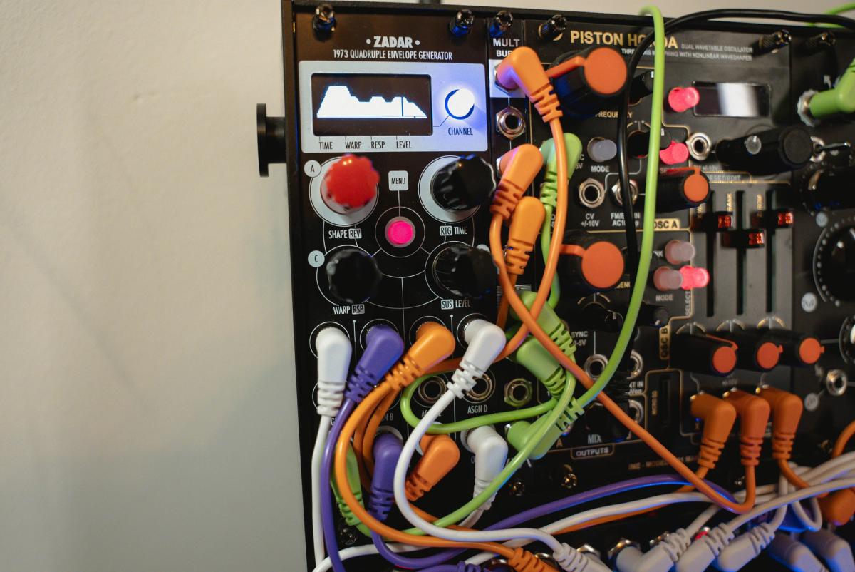 Close-up of a Zadar module with its illuminated waveform display and patched cables