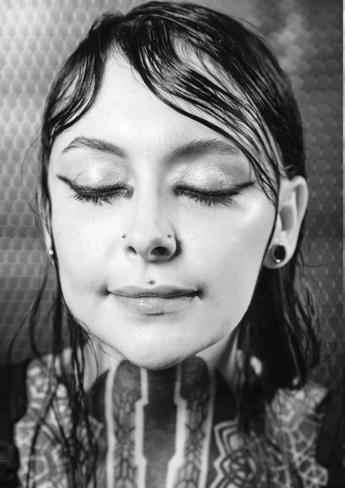 Black and white close-up of Krista with closed eyes and patterned neck tattoos