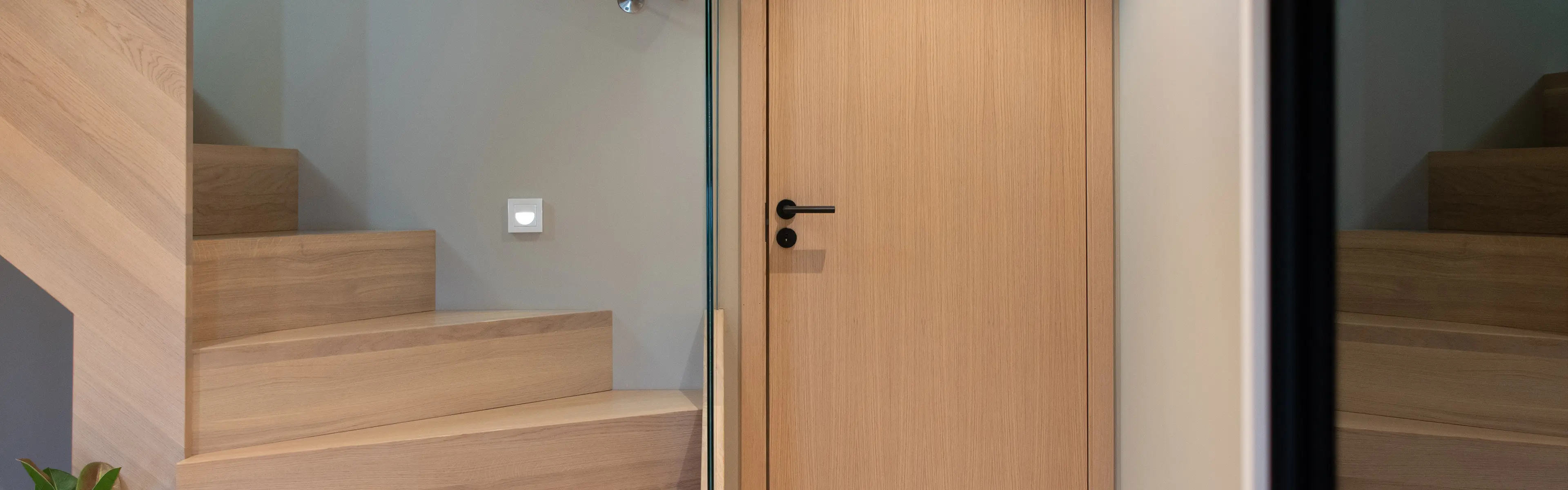 Lys innerdør i eik med sort dørhåndtak og dørvrider.