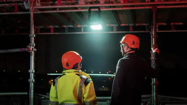 Lyssterk arbeidslampe som henger i stillas på byggeplass.