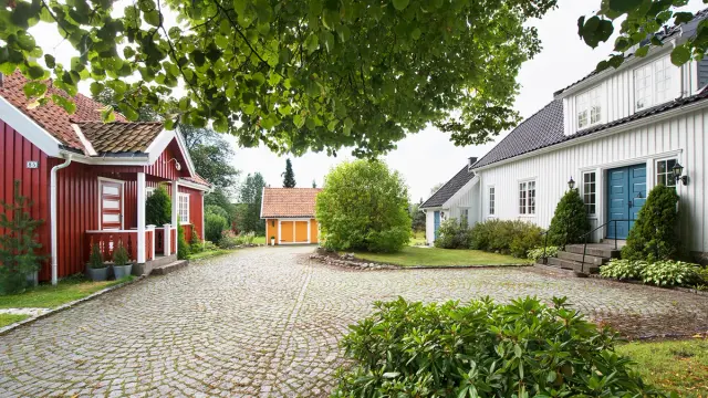 Gårdstun med brostein og hus malt i hvitt, gult og rødt.