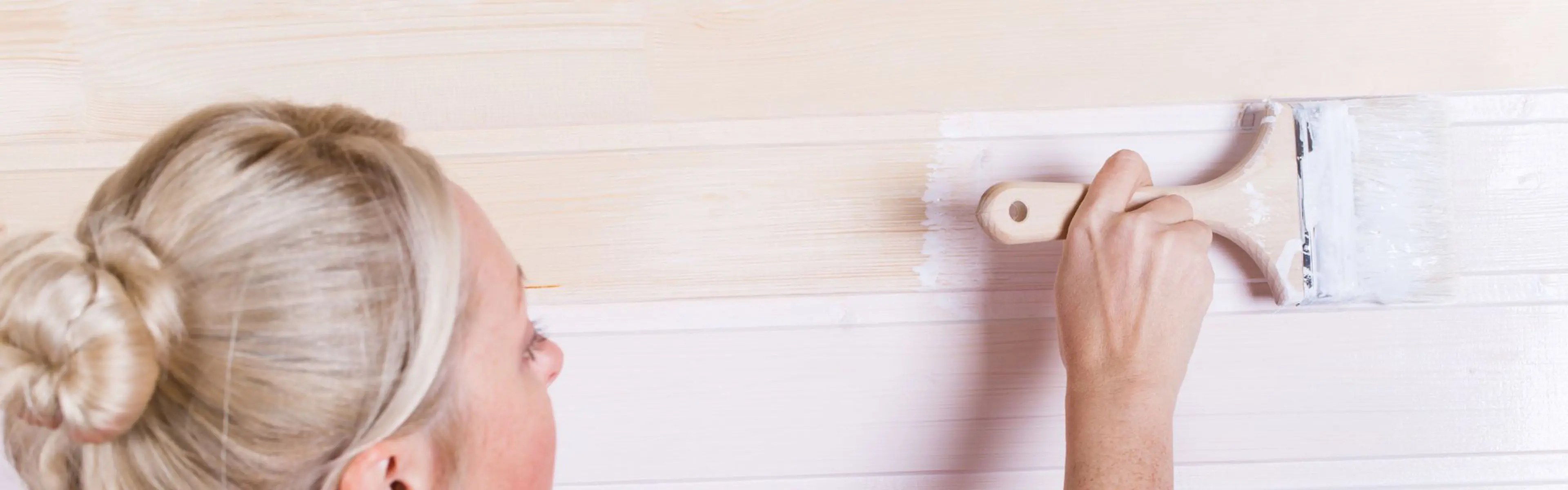 Kvinne som holder på å male panel.