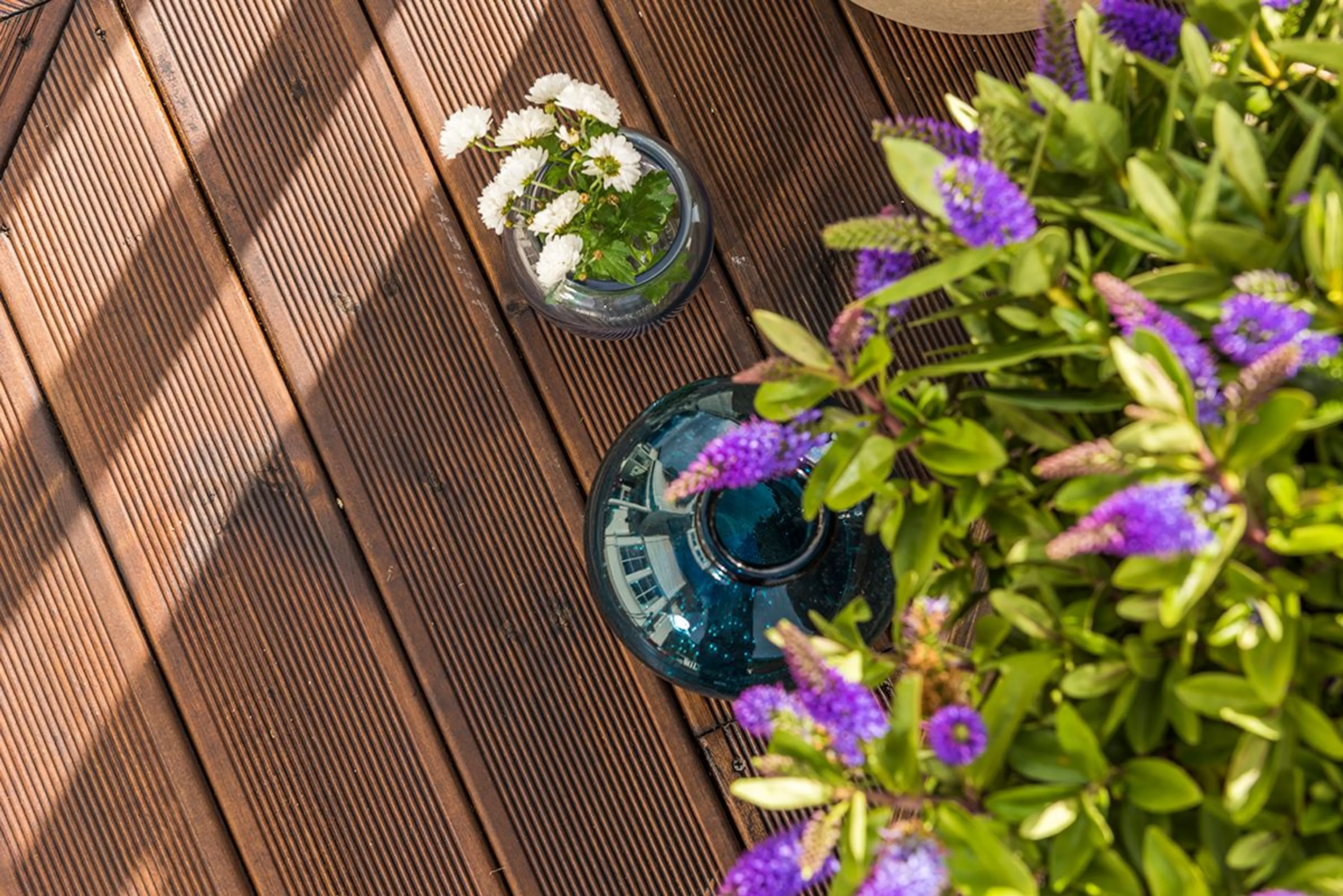 Nærbilde av brunoljet Duo terrassebord med sommerblomster på