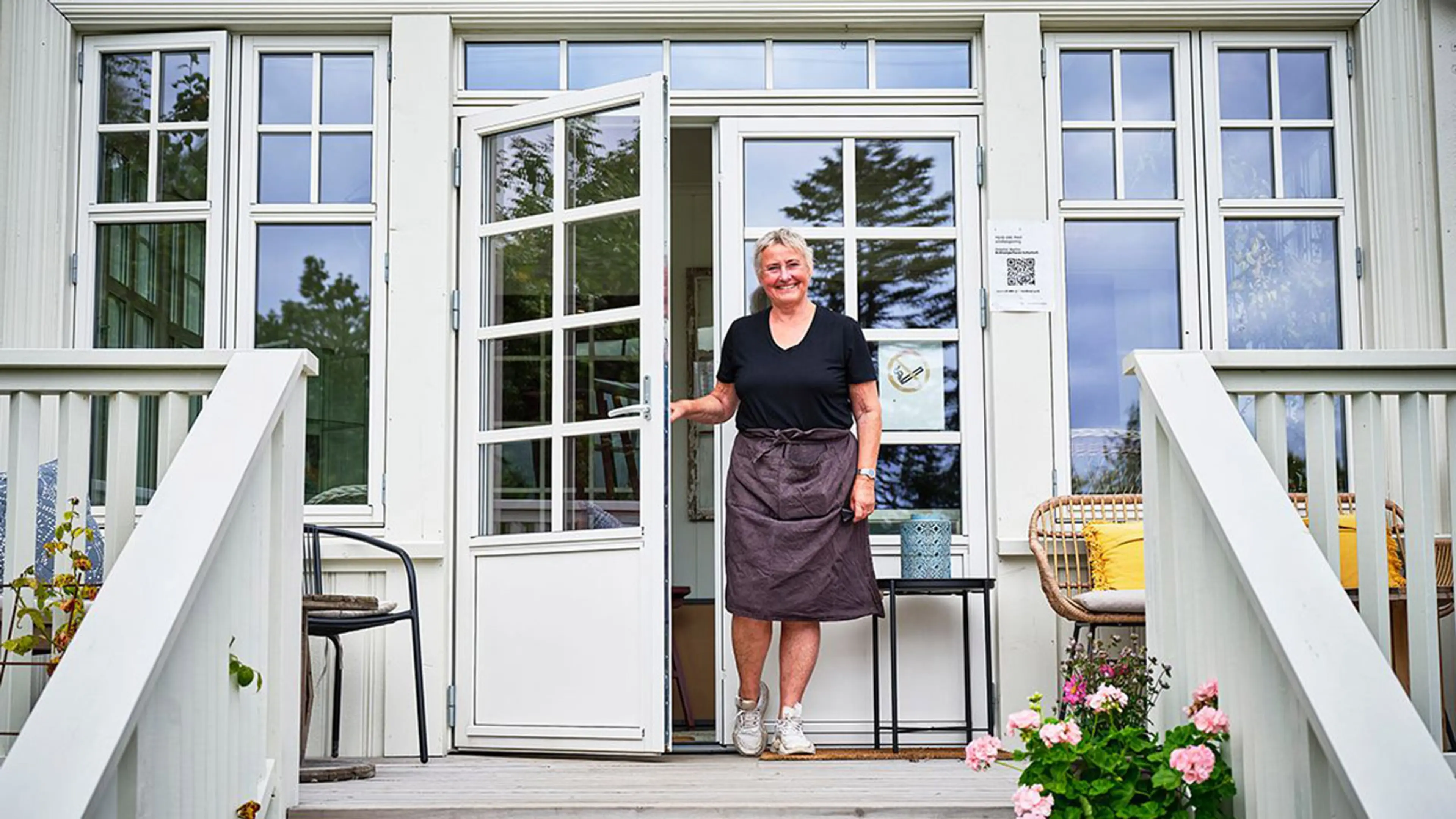 Kvinne er på vei ut av en klassisk balkongdør med sprosser om våren.