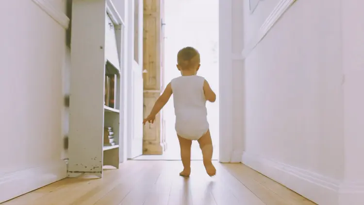 Baby som løper over gulvet i en gang med trinnlydplater for mindre støy.