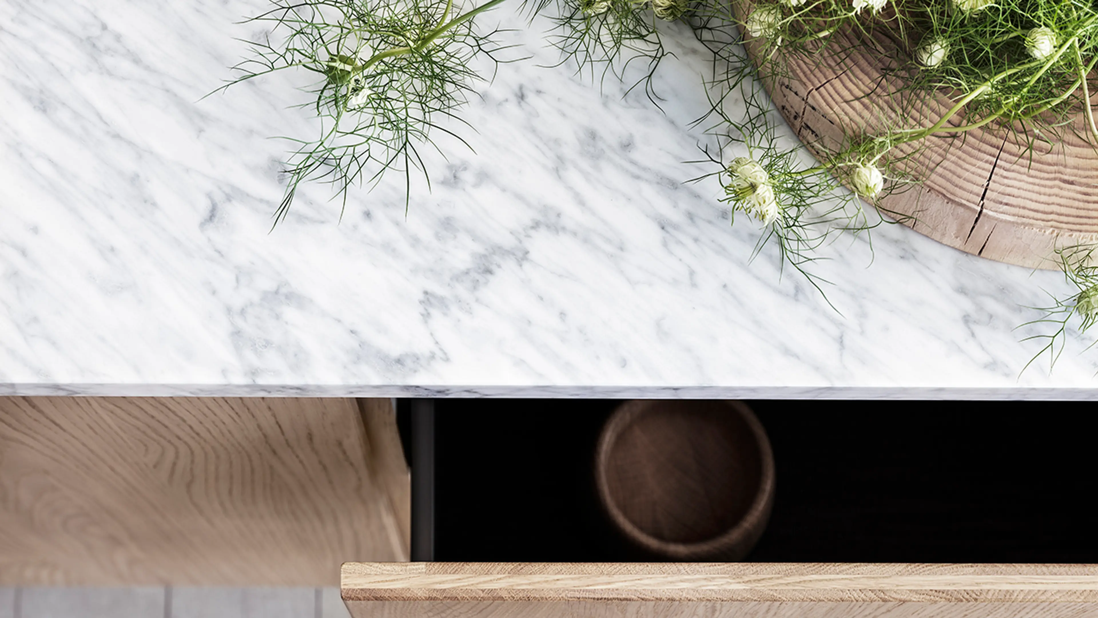 Benkeplate marmor i lyst kjøkken med eikefronter.