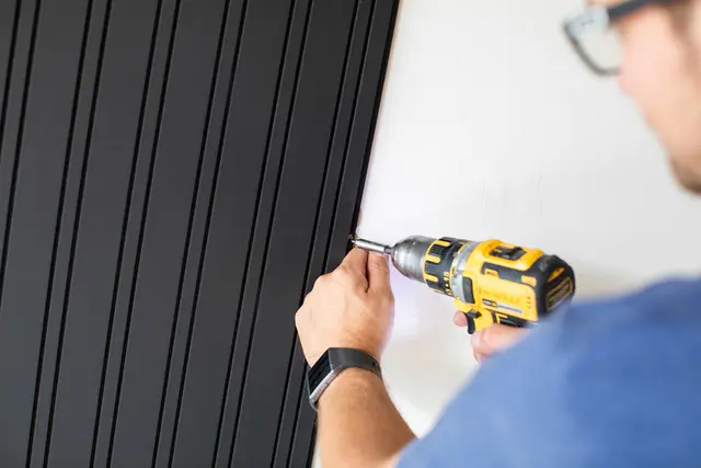 Mann monterer spilepanel på vegg