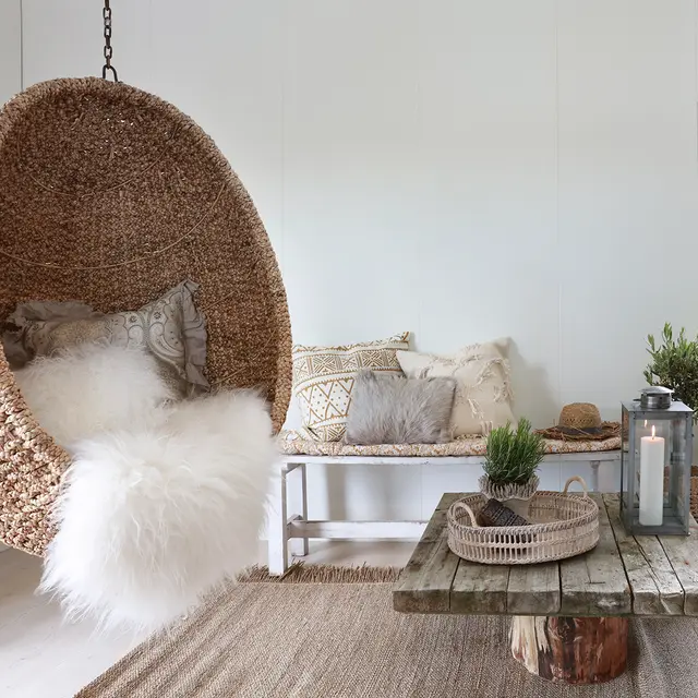 Hvit stue med veggplater og bohemsk stil med treverk og rotting