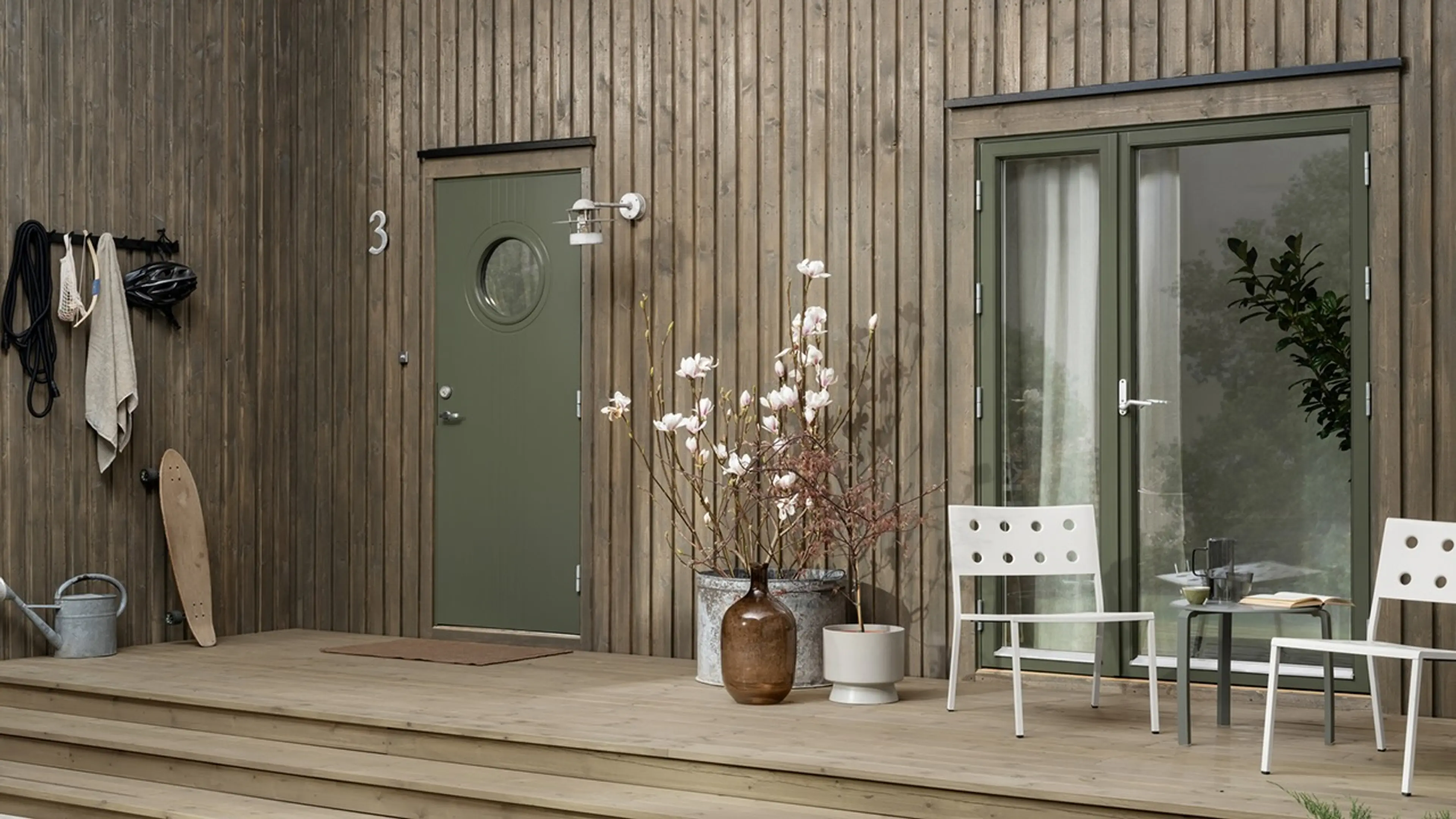 Hus malt med utebeis TREBITT Oljebeis 90031 Eldet Grå, dør: Drygolin Nordic Extreme Vindu og dør 8413 Herregårdsgrønn og TREBITT Terrassebeis 9074 Nordisk Tre.