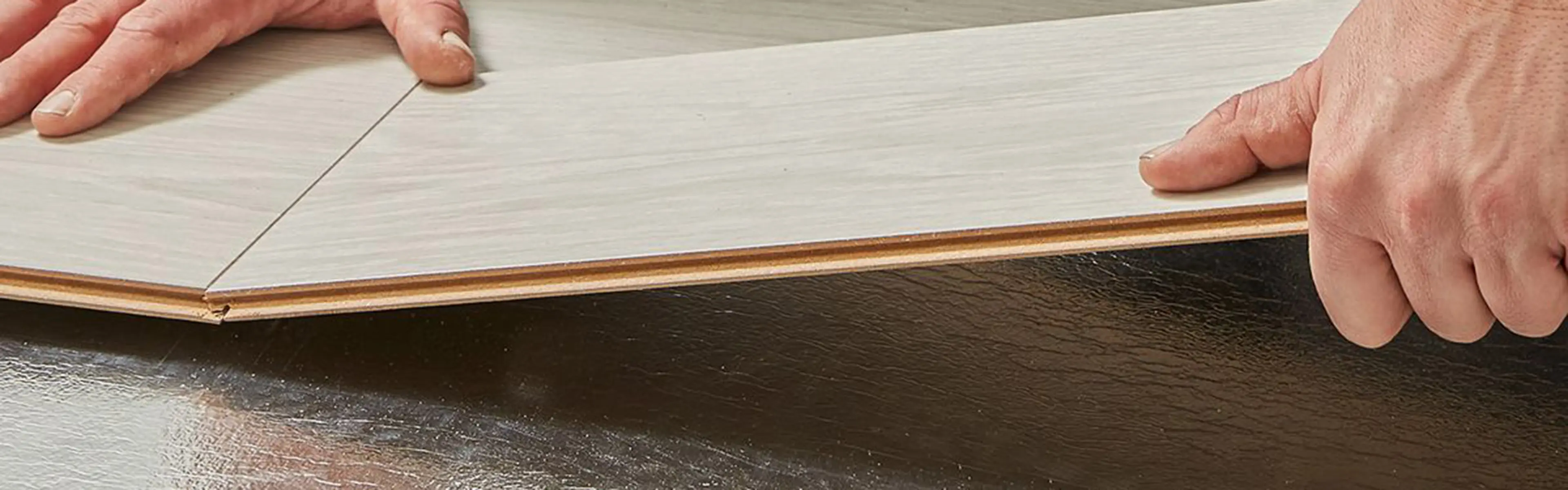 Nærbilde av hender til en person som legger gulv.