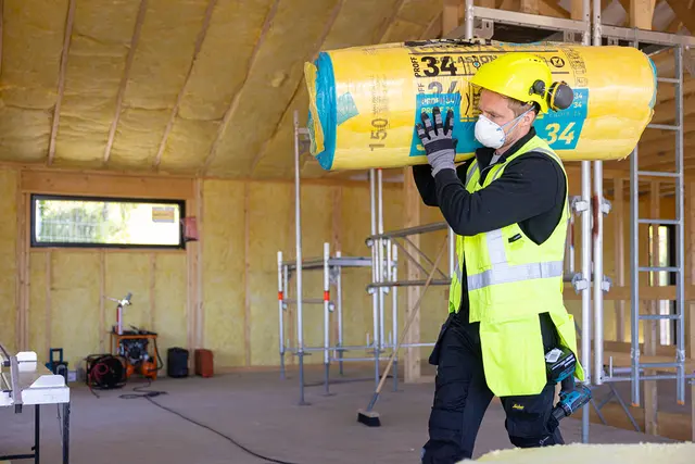 Snekker bærer en rull med Glava 34 isolasjon over skulderen