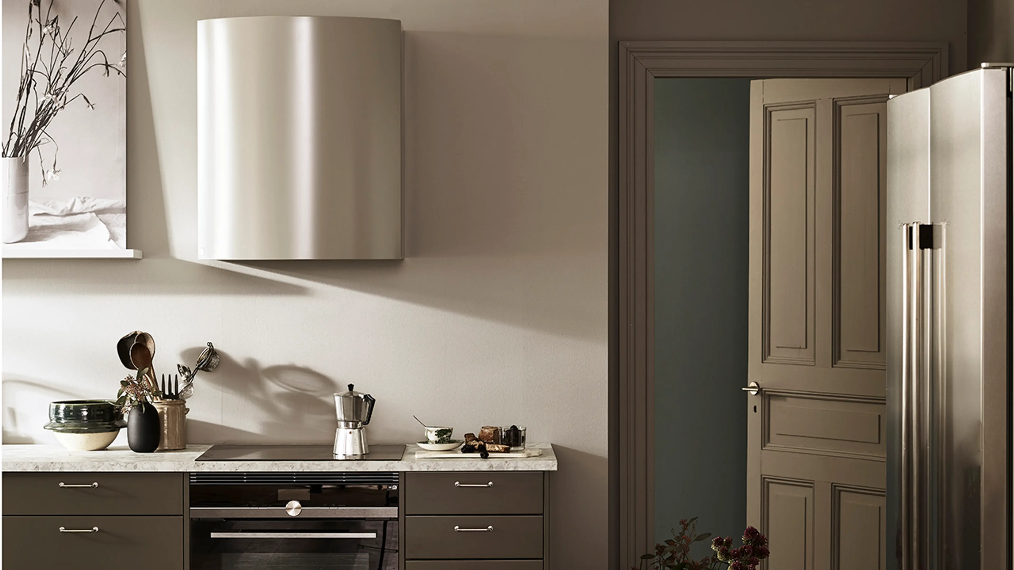 Kjøkkenhette som går ton-i-ton med veggen i et brunt og lyst kjøkken.