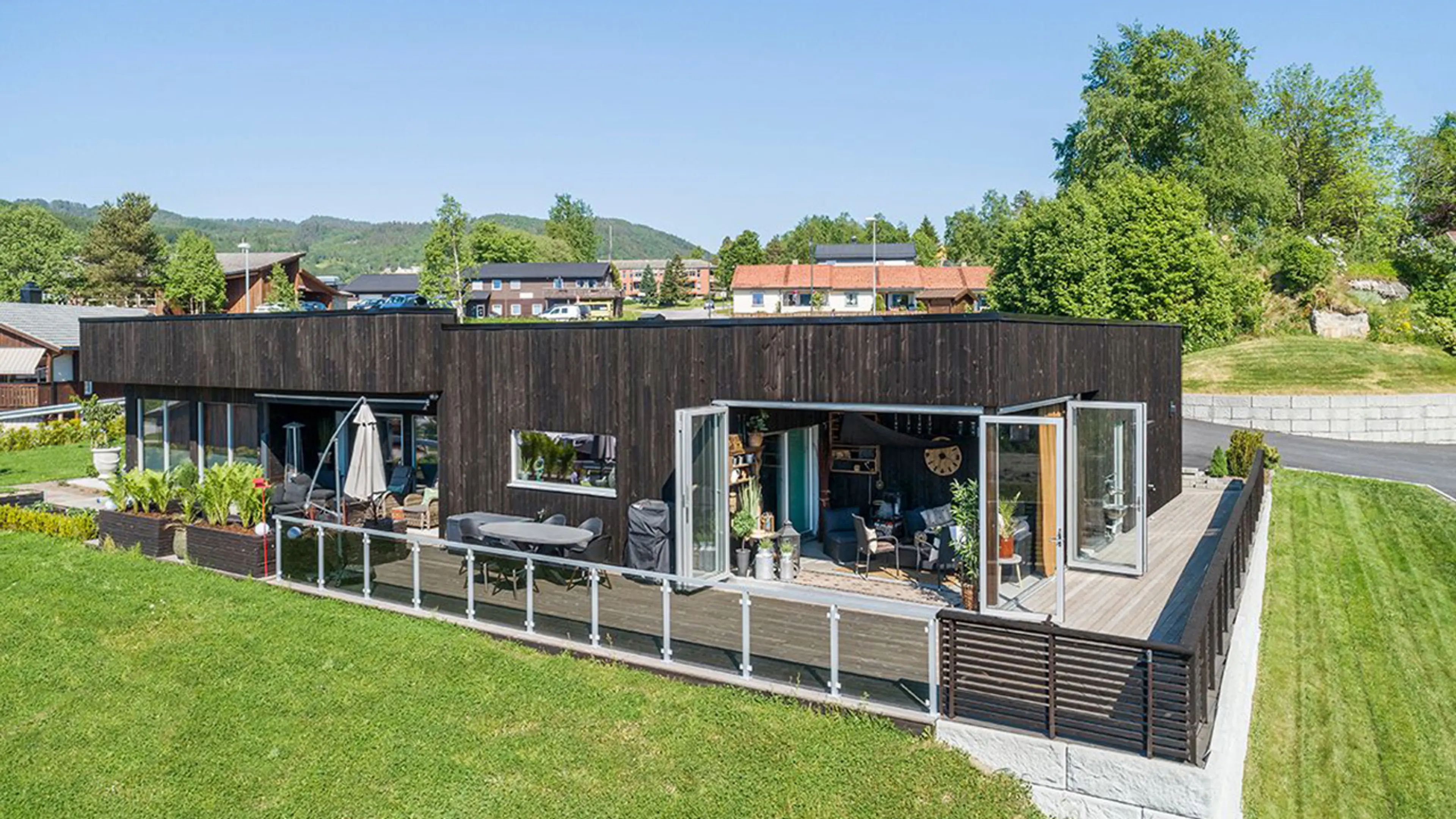 Funkishus med stående kledning og stor terrasse.