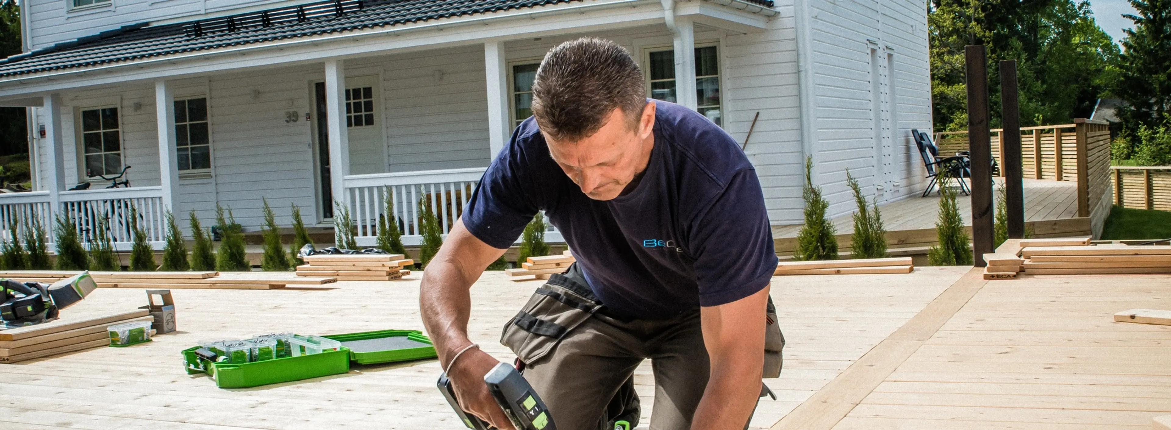Mann som skrur skruer på terrasse.