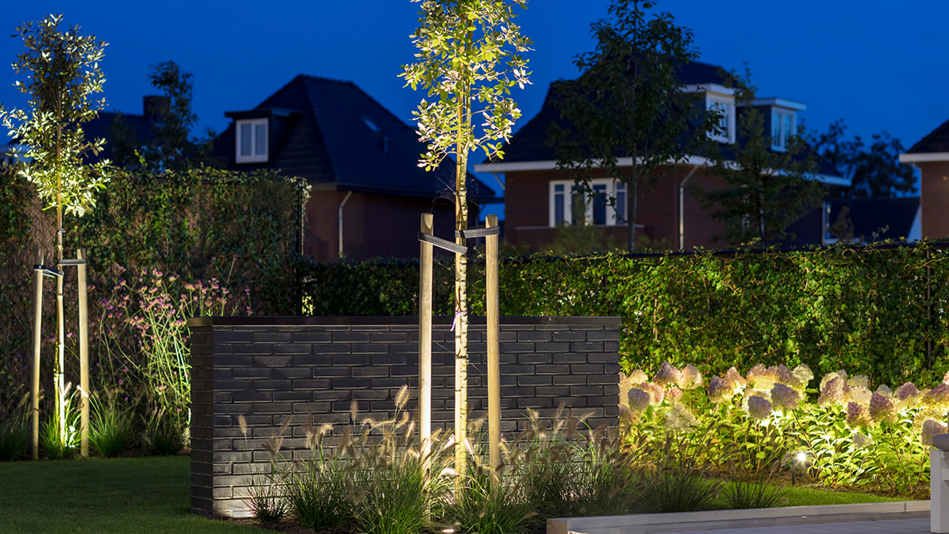 Spotter som hagebelysning i frodige blomsterbed.