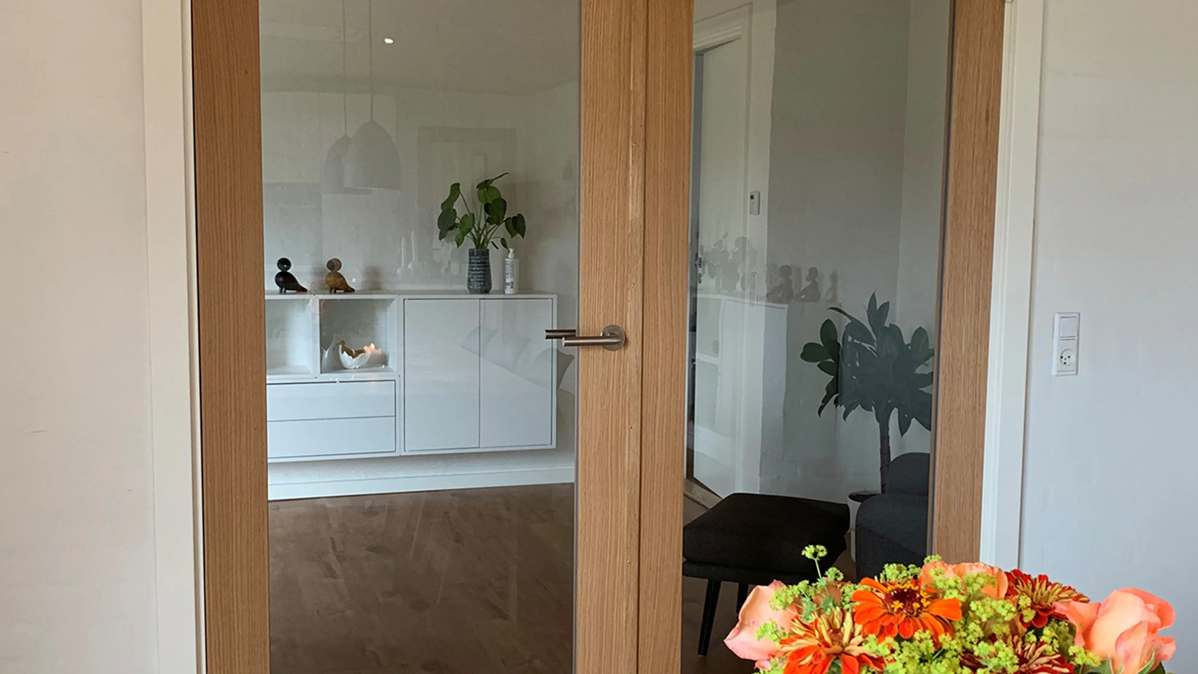 Dobbel innerdør i glass fra kjøkken til stue i lyst treverk.