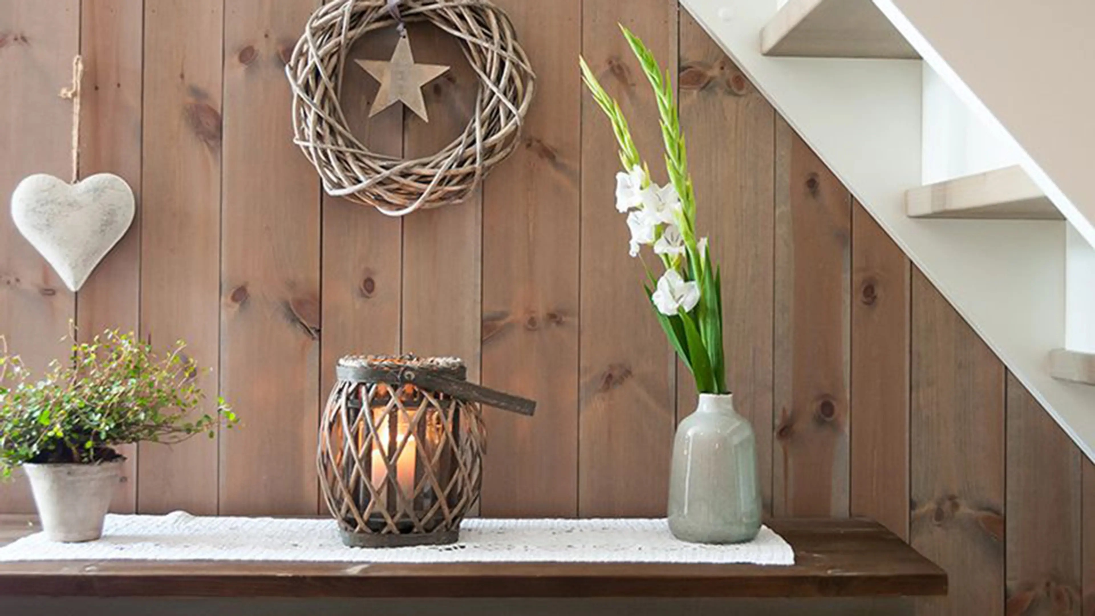 Beiset trepanel på hytte bak en grønn kommode med pyntegjenstander.