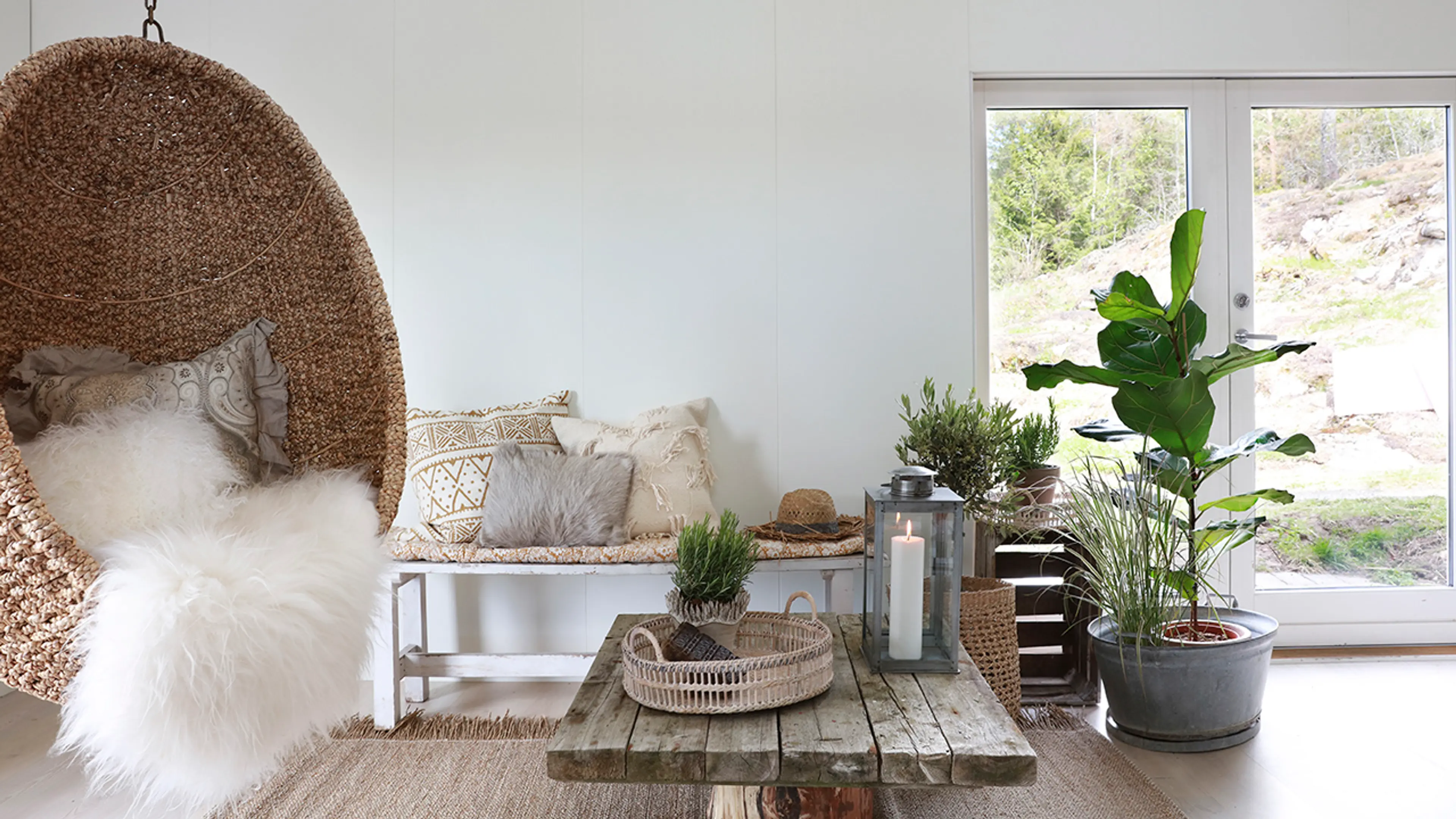 Hvit stue med veggplater og bohemsk stil med treverk og rotting.