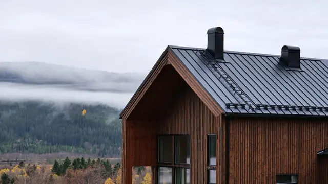 Brunt trehus med svarte takplater aluminium på taket.