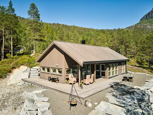nybygget hytte med terrasse og bålpanne. Fjellterreng