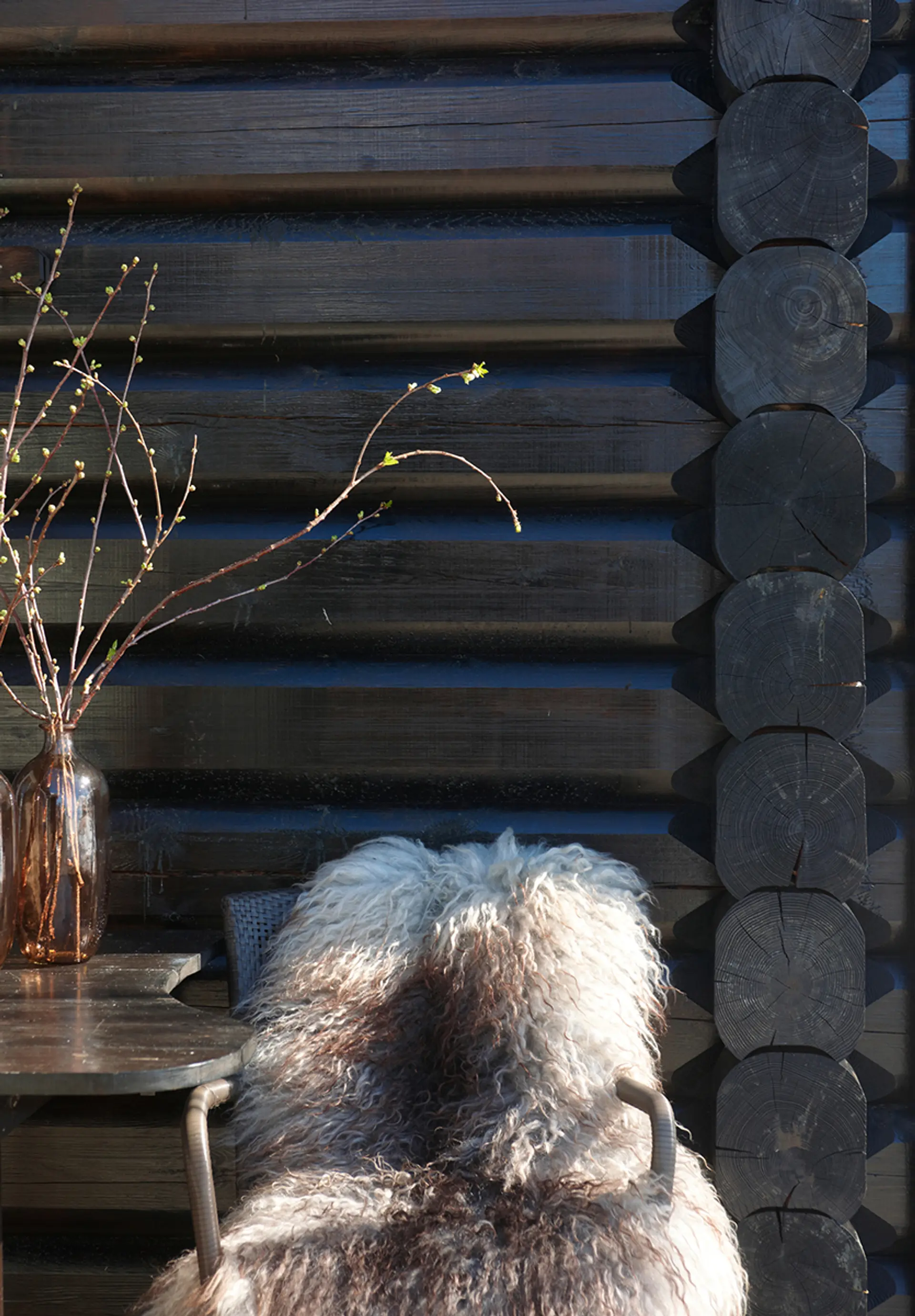 hagestol med saueskinn står inntil en brunbeiset hyttevegg