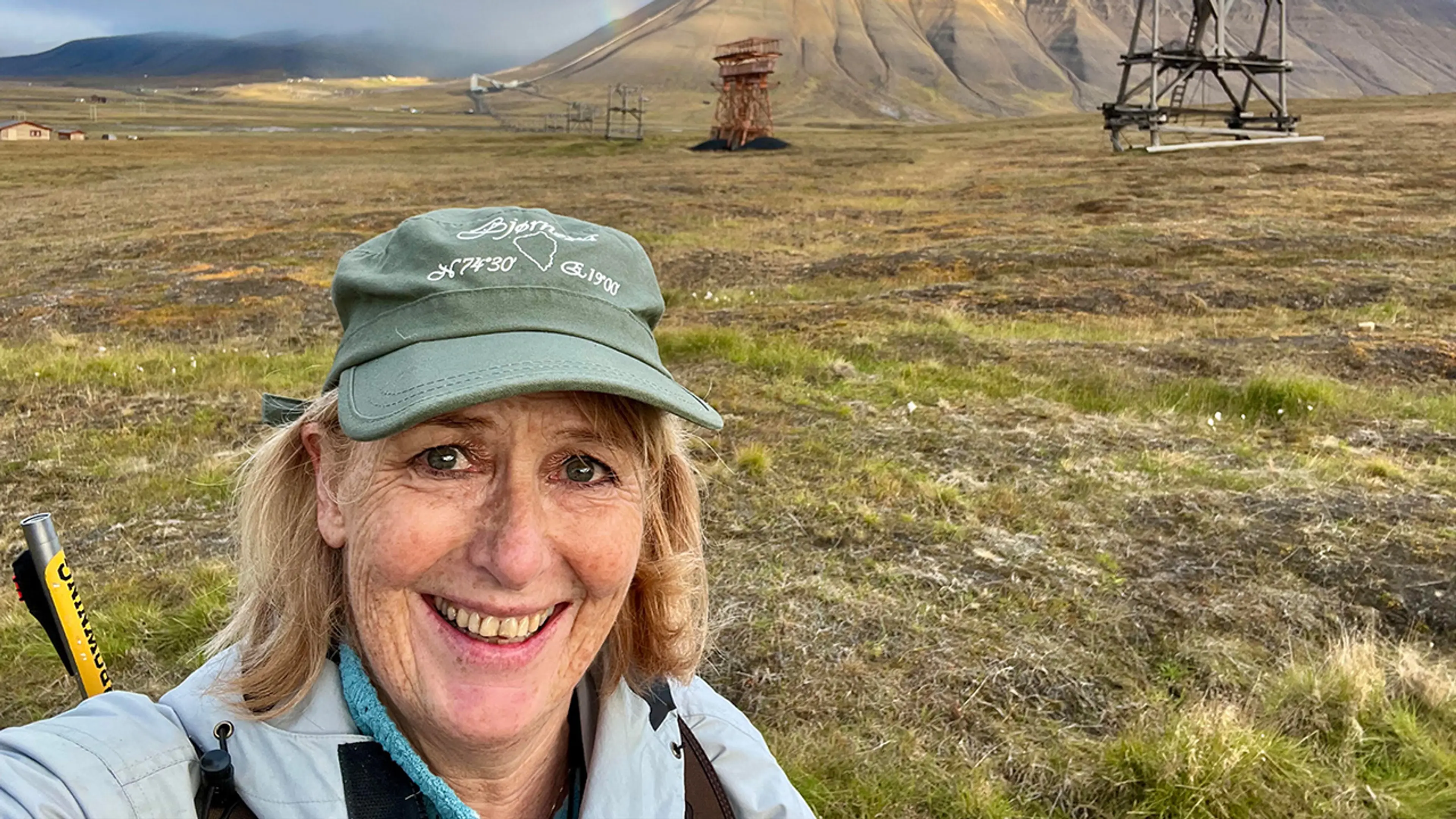 Bilde av avnsiktet til en dame med grønn caps som står ute i naturen.