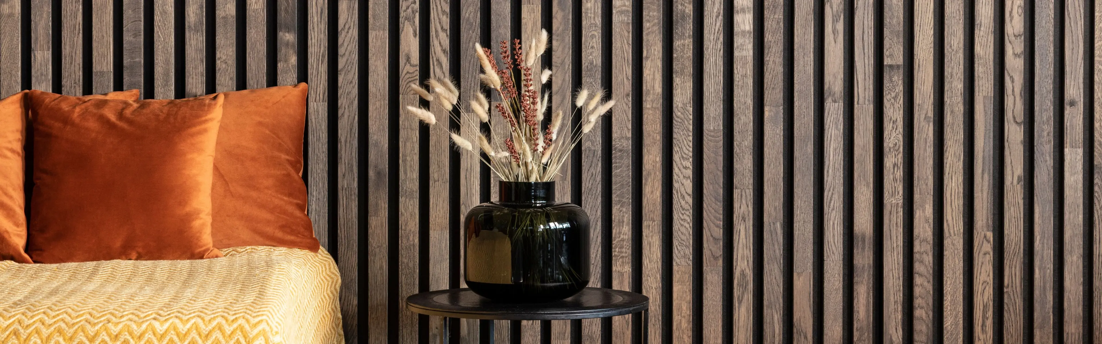 Spilevegg inne med sofa og bord foran.