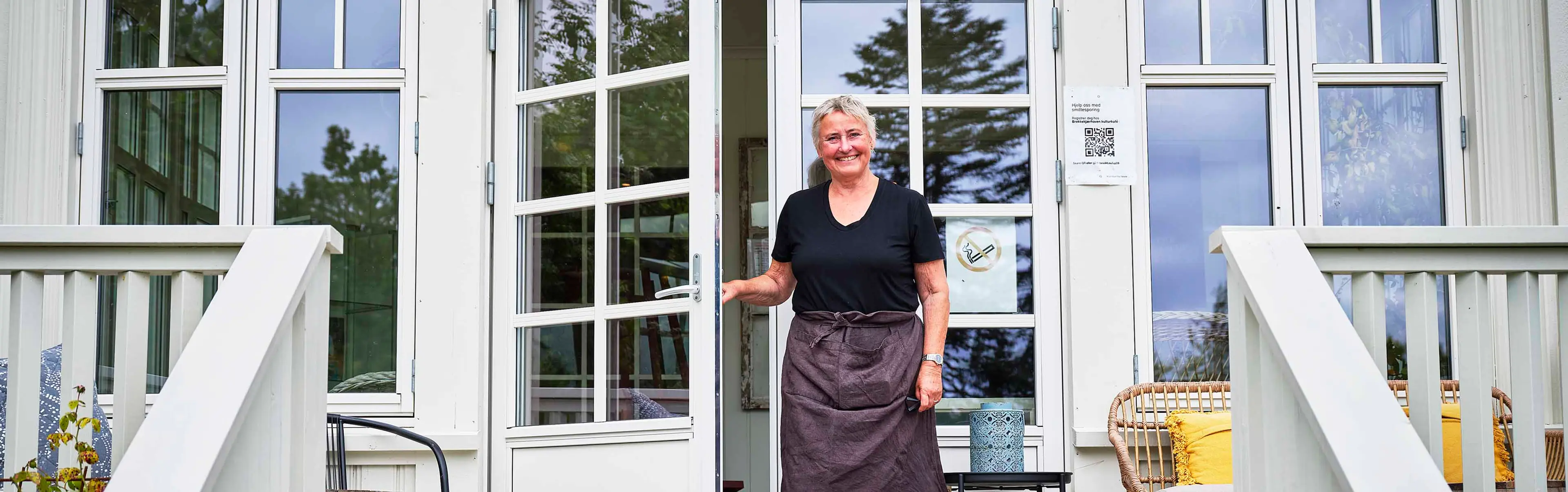 Kvinne er på vei ut av en klassisk balkongdør med sprosser om våren.