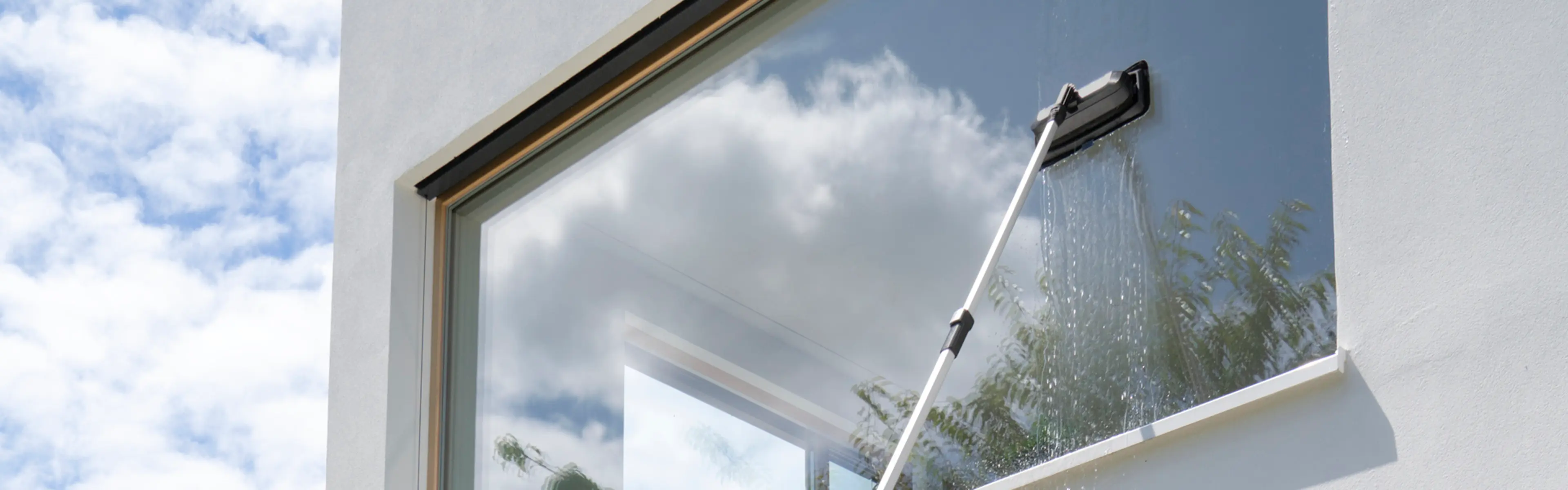 Bilde som viser hvordan vaske vinduer ute som er høyt oppe med forlengerskaft.